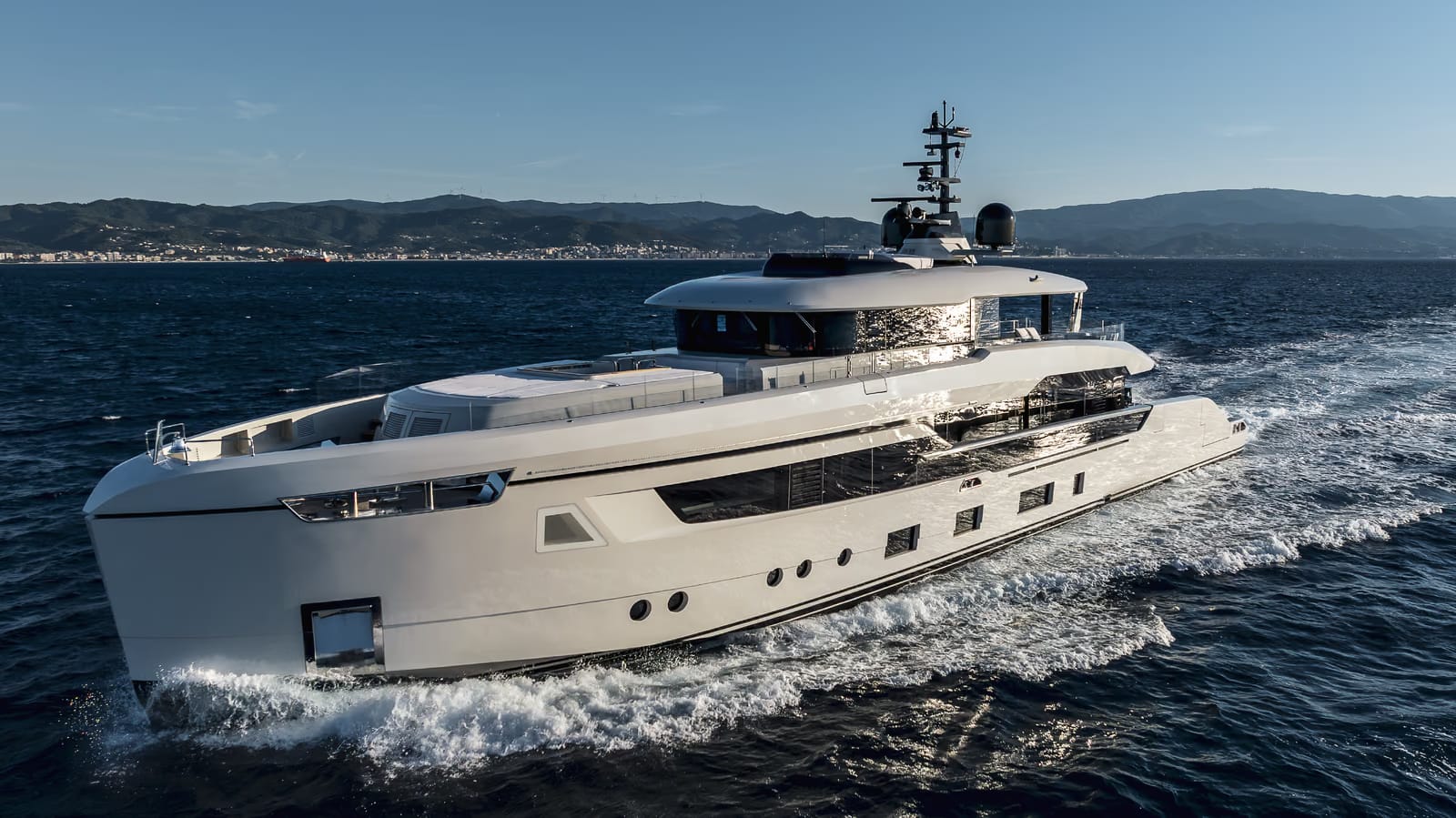 Columbus Atlantique 38 motor yacht cruising at speed on a deep blue sea, seen from the bow, with the coast behind