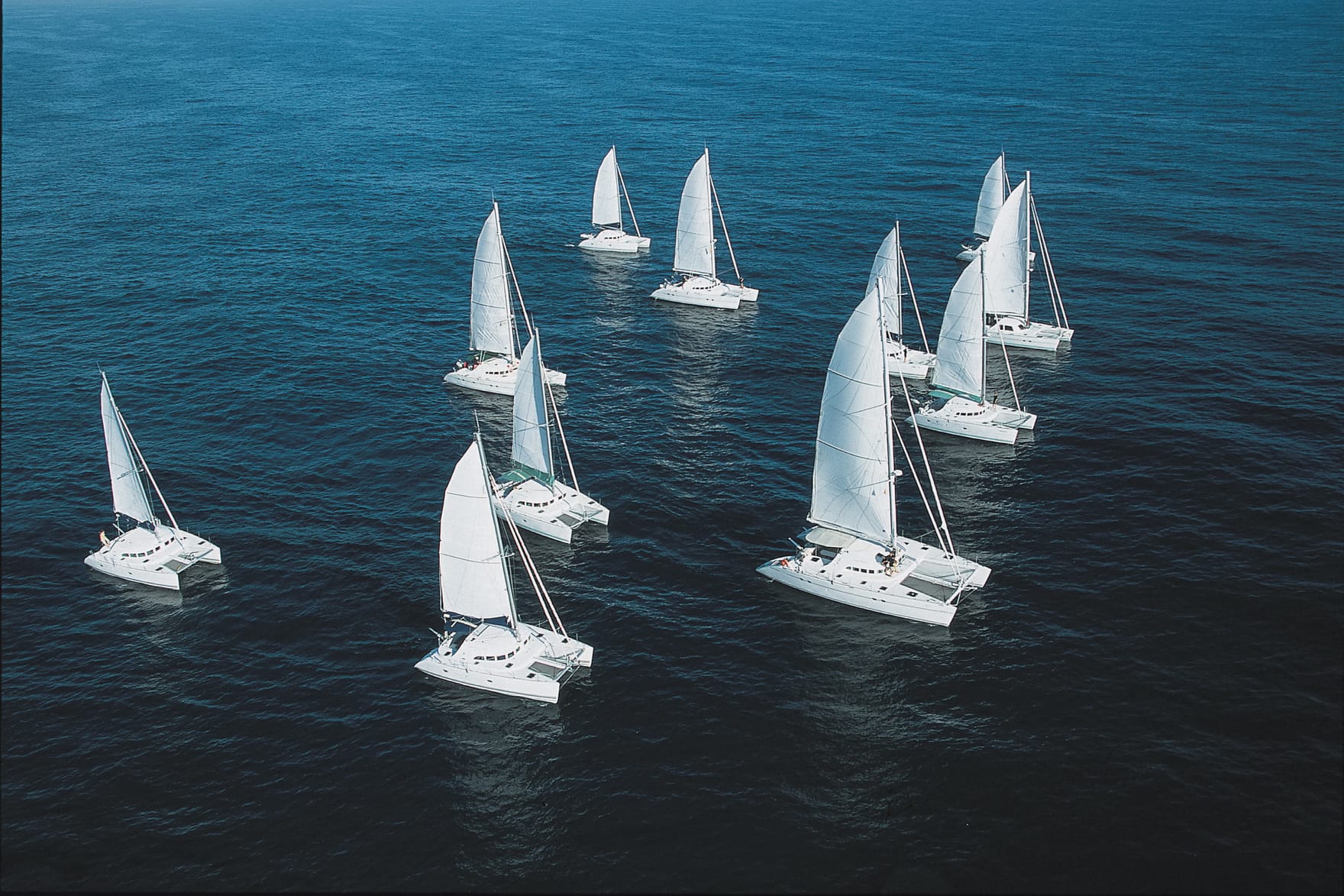A fleet of Lagoon catamarans sailing together on open water
