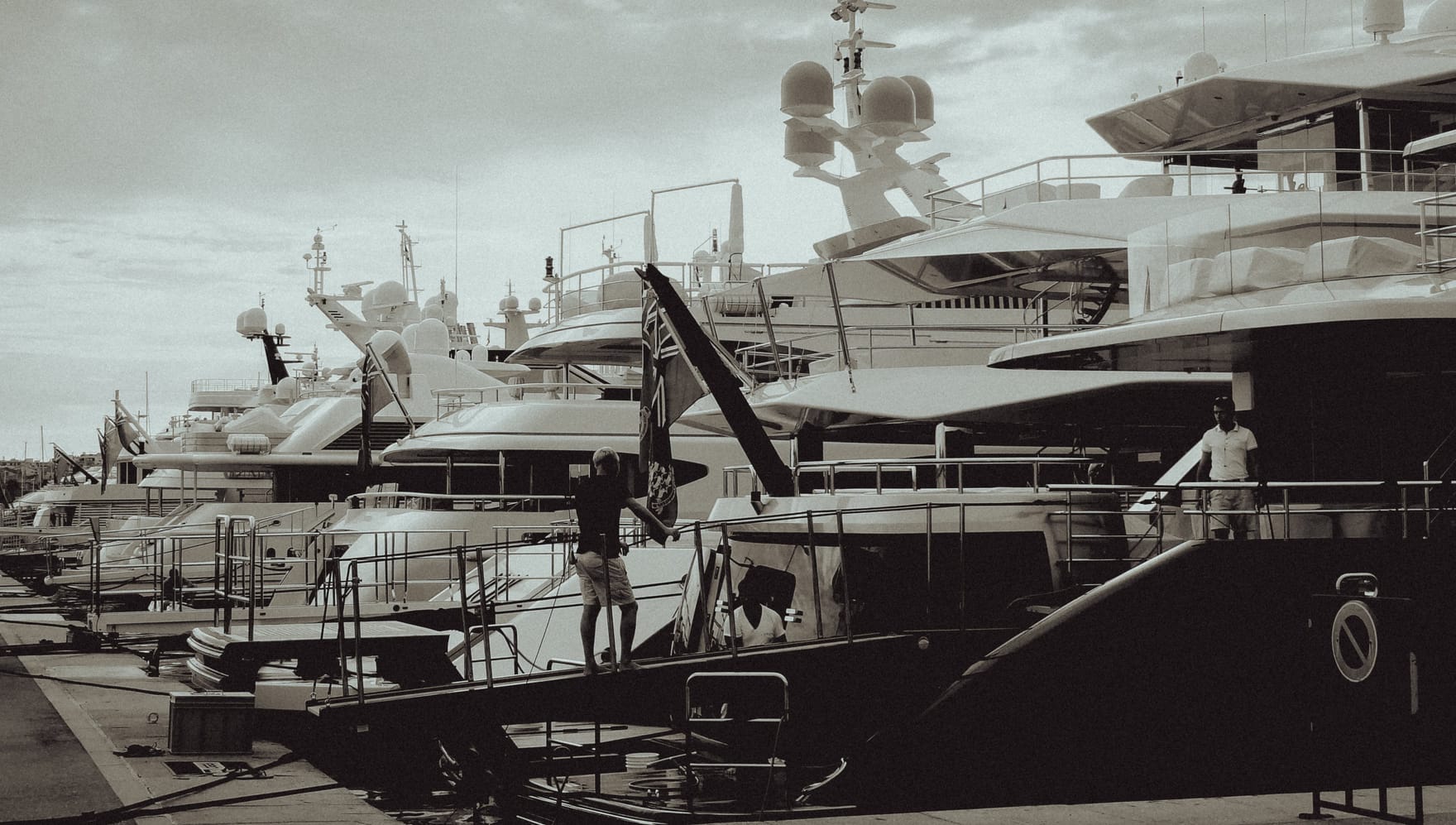 Crew at work on a row of managed yachts moored stern-to along a quay